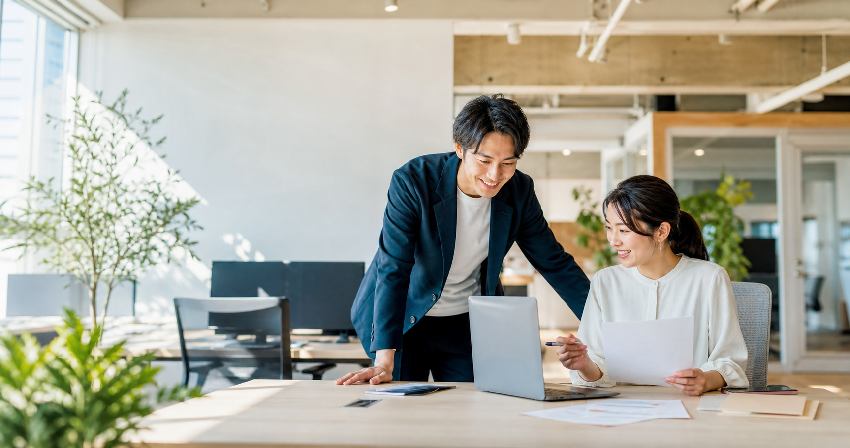 明るいオフィスで自然に打ち合わせをする日本人社員